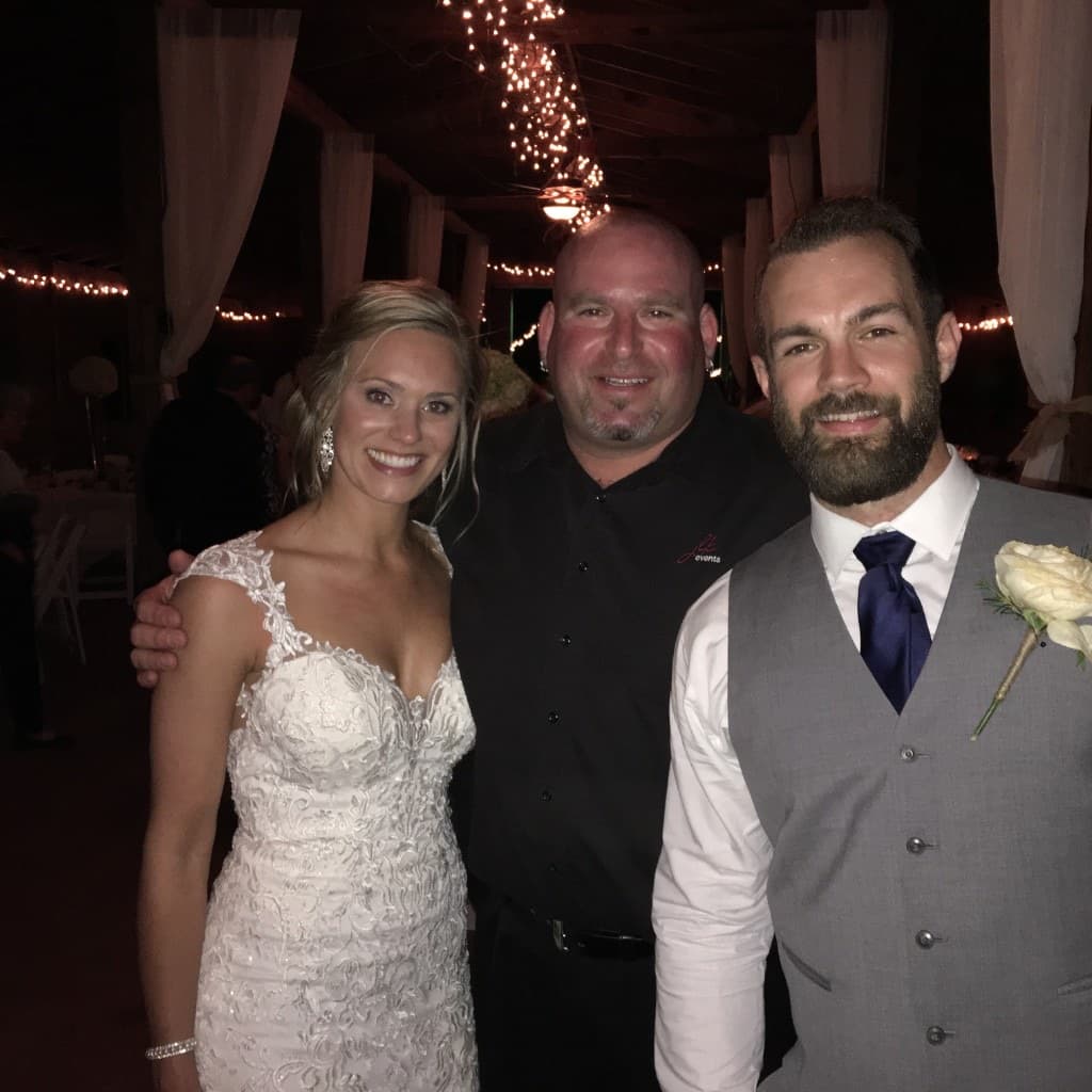 Gary Lucca with a bride in lace and groom in a grey vest under string lights at a Lowcountry reception