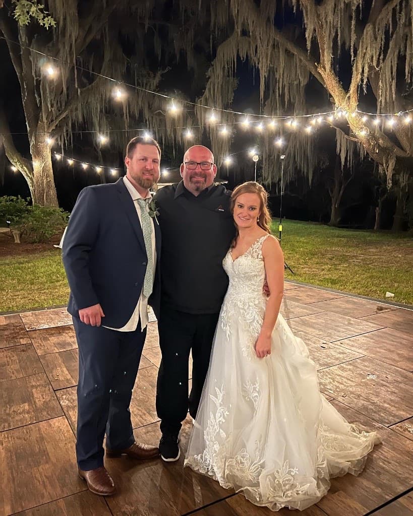 Gary Lucca with a bride and groom on a Lowcountry dance floor under Spanish moss and bistro lights