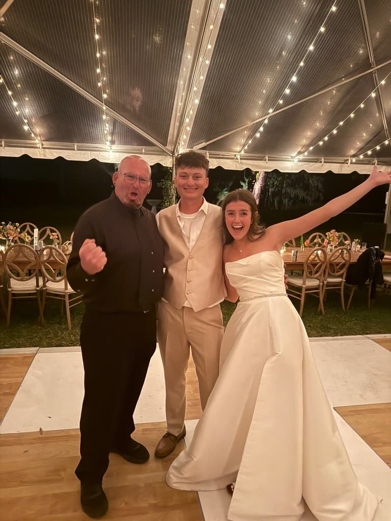 Gary Lucca celebrating with a young bride and groom on the dance floor of a tented Lowcountry reception