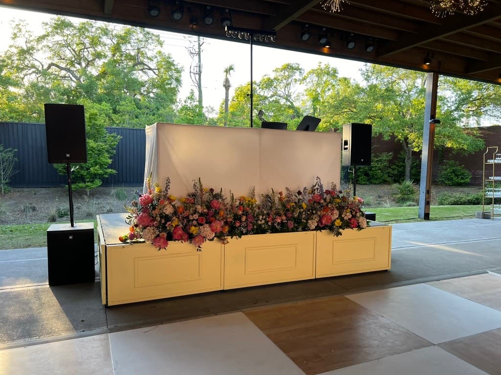DJ booth fronted by a cascading floral installation at a Lowcountry garden wedding