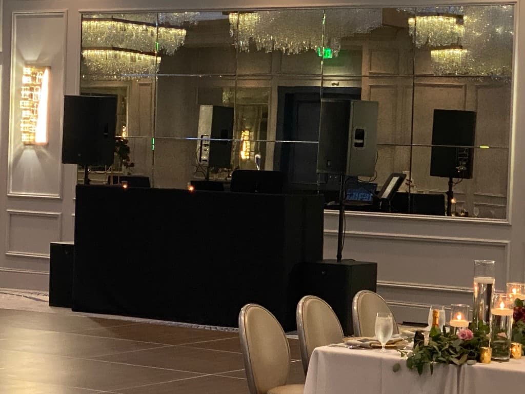 Refined ballroom setup with crystal chandelier reflections and black linen DJ booth for a Savannah reception