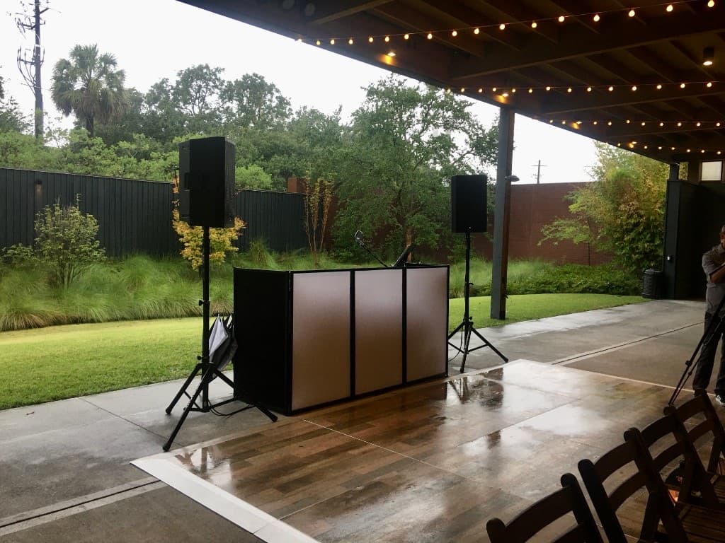 Covered patio DJ booth with speaker stands and string lights ready for a rain-plan Lowcountry wedding