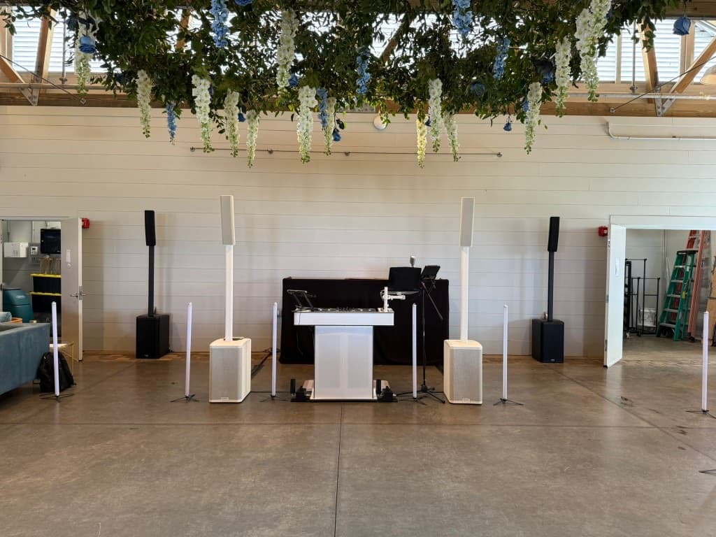 White column-speaker stack with hanging florals at a spring Lowcountry wedding reception